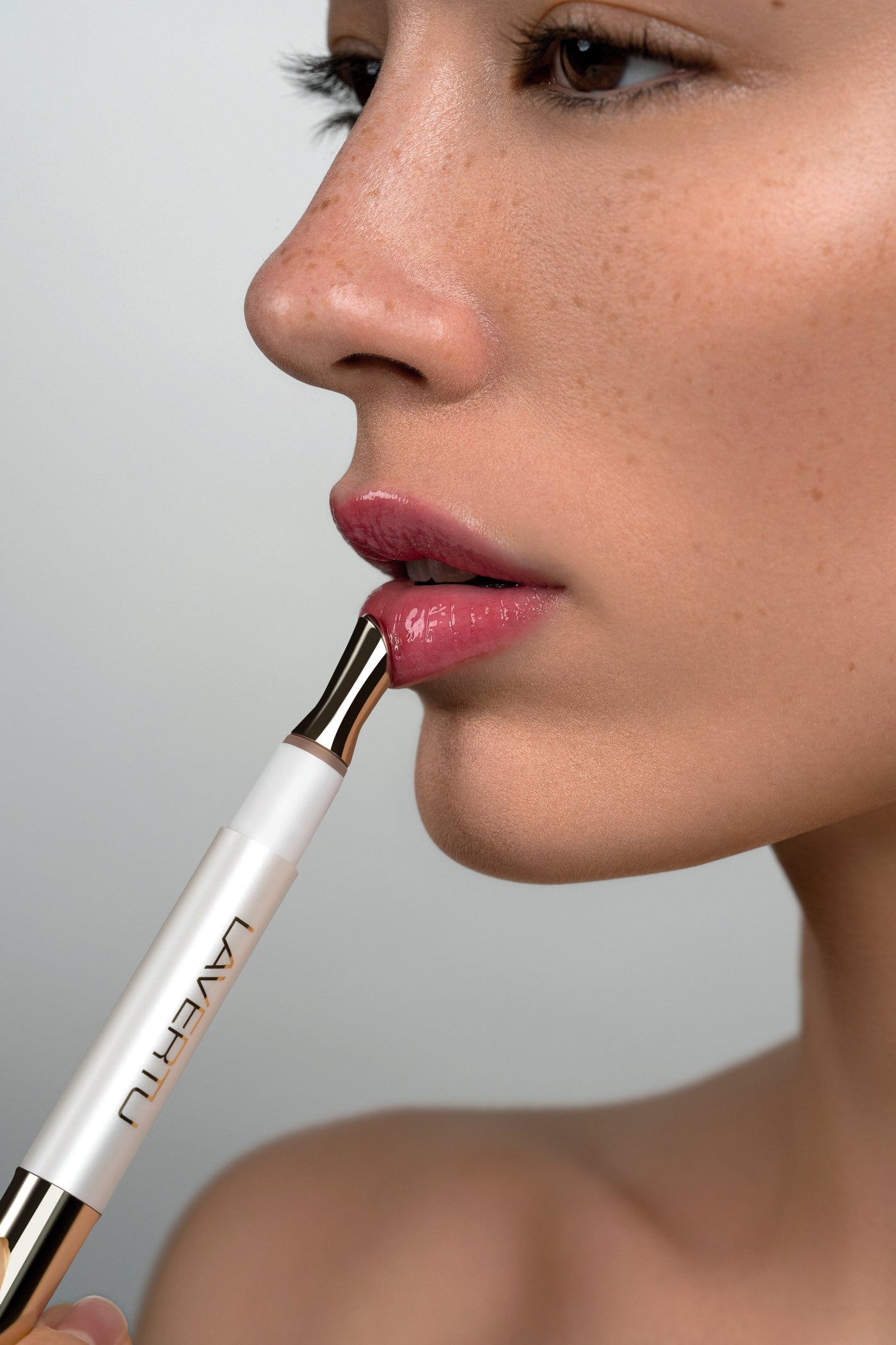Model applying Lavertu Renewal Adaptive Lip Oil for a natural glossy finish and subtle pink tint.